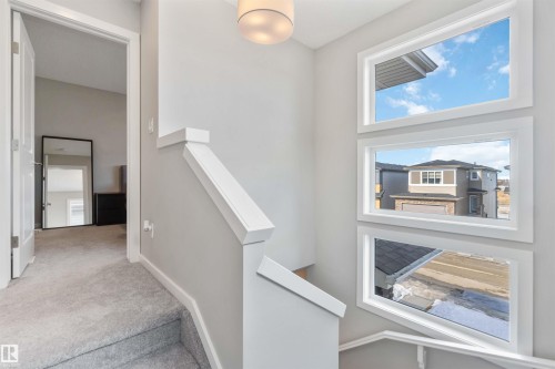 Staircase featuring a modern white railing, grey carpeted steps, and three rectangular windows providing natural light - 29 Gambel Loop, Spruce Grove, AB - Indoor Photo Showing Other Room