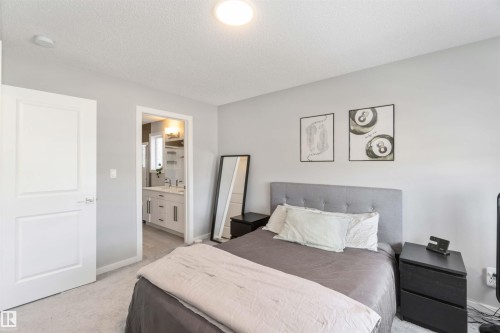 This bedroom features light gray walls, a gray upholstered headboard, and a white interior door - 29 Gambel Loop, Spruce Grove, AB - Indoor Photo Showing Bedroom