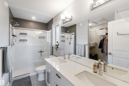 Bathroom featuring a double vanity with an expansive mirror, a glass-enclosed shower, and a private water closet - 29 Gambel Loop, Spruce Grove, AB - Indoor Photo Showing Bathroom