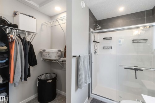 This bathroom features a contemporary shower with dark gray tiling and a glass enclosure - 29 Gambel Loop, Spruce Grove, AB - Indoor With Storage