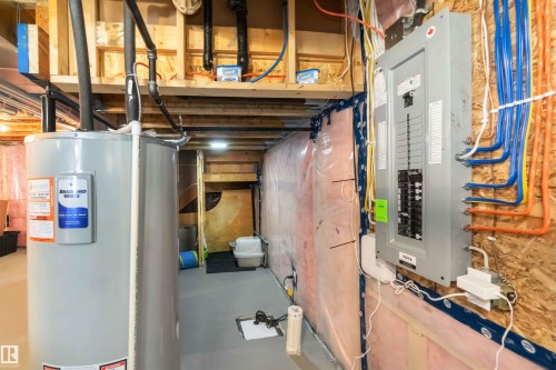 The property features a hot water tank and an electrical panel, with visible wiring and plumbing - 29 Gambel Loop, Spruce Grove, AB - Indoor Photo Showing Basement