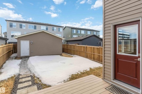 The property features a private backyard with a wooden fence, a detached utility building, and a stone walkway - 29 Gambel Loop, Spruce Grove, AB - Outdoor With Deck Patio Veranda With Exterior