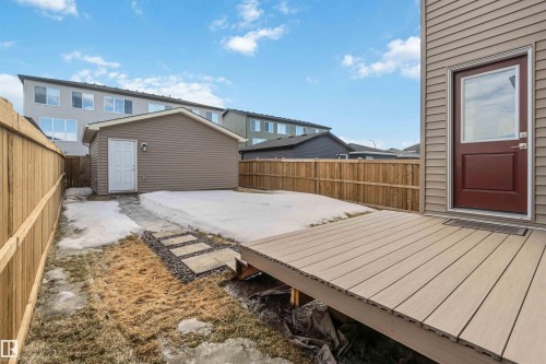 The property features a private backyard with a wooden fence, a detached shed, a deck, and stepping stones - 29 Gambel Loop, Spruce Grove, AB - Outdoor With Deck Patio Veranda With Exterior