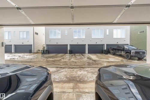 View from inside the garage, showing the paved driveway and garage doors of the surrounding properties - 29 Gambel Loop, Spruce Grove, AB - Indoor Photo Showing Garage