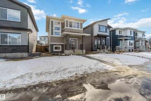 The property features a two-story design with a light brown facade and a stone-clad porch column - 29 Gambel Loop, Spruce Grove, AB - Outdoor With Facade