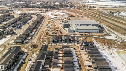 Aerial view of a developed residential area with numerous detached properties and townhomes, featuring a nearby commercial building and highway access - 29 Gambel Loop, Spruce Grove, AB - Outdoor With View