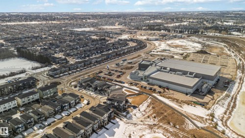 Aerial view showcasing the residential area with various properties, a large commercial building, and a partially frozen body of water - 29 Gambel Loop, Spruce Grove, AB - Outdoor With View