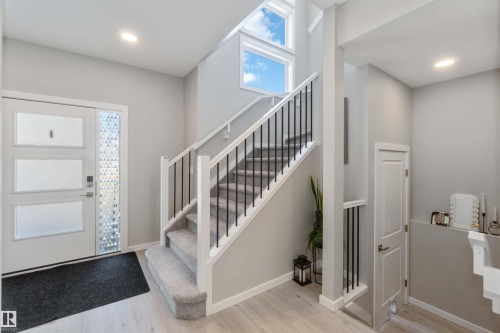 Inviting entryway featuring a white front door with frosted glass panels, a carpeted staircase with dark balusters, and light wood flooring - 29 Gambel Loop, Spruce Grove, AB - Indoor Photo Showing Other Room