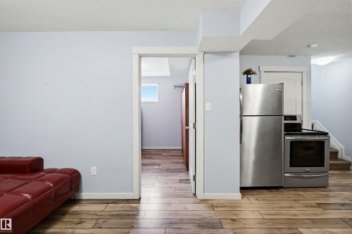 This property features light wood flooring, light blue walls, and a stainless steel refrigerator and oven - 2812 16 Avenue, Edmonton, AB - Indoor