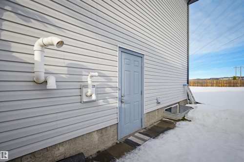 The property features light gray horizontal siding, a light blue exterior door, and a foundation with a textured finish - 2812 16 Avenue, Edmonton, AB - Outdoor With Exterior