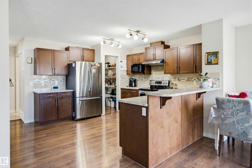 This kitchen features wood cabinetry, stainless steel appliances, and a tiled backsplash - 2812 16 Avenue, Edmonton, AB - Indoor Photo Showing Kitchen
