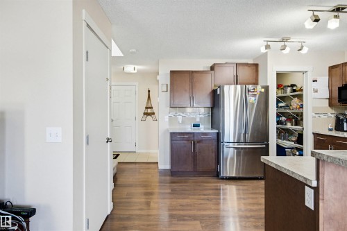 The kitchen features stainless steel appliances, dark wood cabinetry, and a pantry with shelving - 2812 16 Avenue, Edmonton, AB - Indoor Photo Showing Kitchen