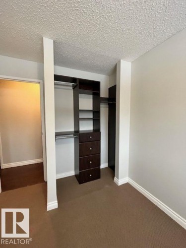 This space features built-in closet organizers with shelving, hanging rods, and drawers, providing versatile storage solutions - 4 10836 116 Street, Edmonton, AB - Indoor