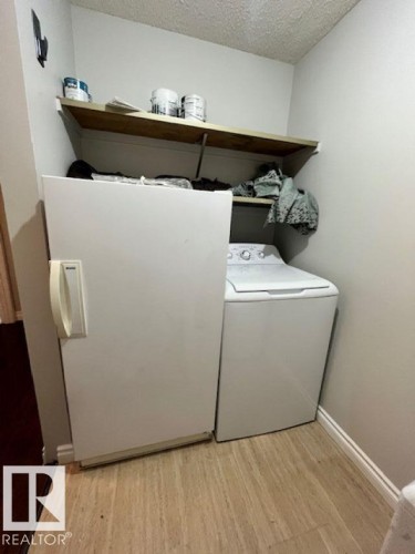 This utility area features a top-loading washing machine and a freestanding freezer - 4 10836 116 Street, Edmonton, AB - Indoor Photo Showing Laundry Room