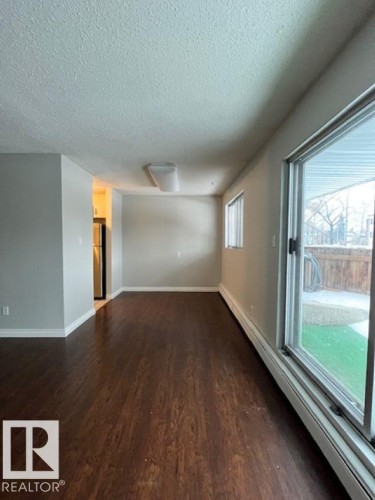 This property features dark wood flooring, light grey walls, and white trim - 4 10836 116 Street, Edmonton, AB - Indoor Photo Showing Other Room