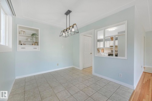 Dining area featuring tiled flooring, a built-in display cabinet, and a modern chandelier - 15704 91 Avenue, Edmonton, AB - Indoor Photo Showing Other Room