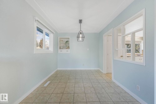 This room features tiled flooring, a window providing natural light, and a modern geometric pendant light fixture - 15704 91 Avenue, Edmonton, AB - Indoor Photo Showing Other Room