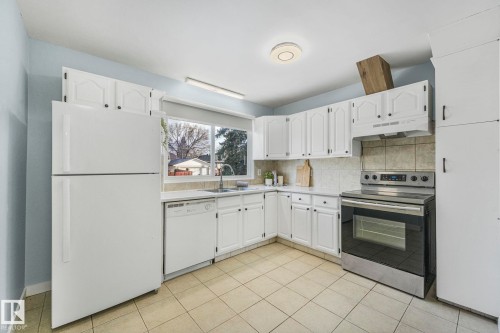 The kitchen features white cabinetry, a built-in oven, and a refrigerator - 15704 91 Avenue, Edmonton, AB - Indoor Photo Showing Kitchen
