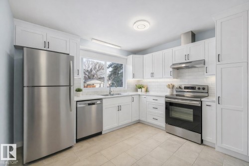 The kitchen features white cabinetry, stainless steel appliances, and a tiled floor - 15704 91 Avenue, Edmonton, AB - Indoor Photo Showing Kitchen