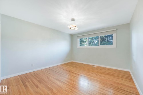 Room featuring hardwood floors, a window with roller shades, and a modern ceiling light fixture - 15704 91 Avenue, Edmonton, AB - Indoor Photo Showing Other Room