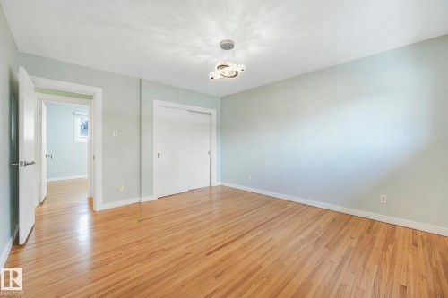 This room features light hardwood flooring, light-colored walls, and a modern ceiling light fixture - 15704 91 Avenue, Edmonton, AB - Indoor Photo Showing Other Room