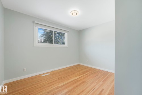 This room features light hardwood flooring, a window with a roller shade, and light-colored walls - 15704 91 Avenue, Edmonton, AB - Indoor Photo Showing Other Room