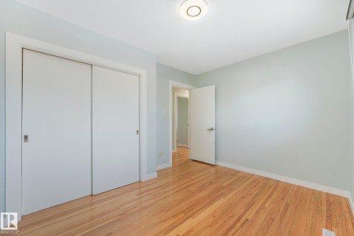 Room featuring hardwood floors, a closet with sliding doors, and a ceiling-mounted light fixture - 15704 91 Avenue, Edmonton, AB - Indoor Photo Showing Other Room