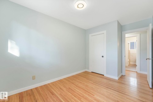 Room with hardwood floors, light blue walls, and a white ceiling with a flush-mount light fixture - 15704 91 Avenue, Edmonton, AB - Indoor Photo Showing Other Room