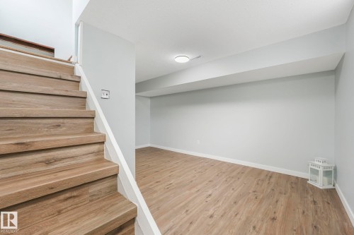 The property features a staircase with wood-look treads and white risers, leading to an interior space with light-colored walls and wood-look flooring - 15704 91 Avenue, Edmonton, AB - Indoor Photo Showing Other Room