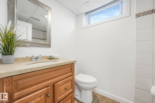 Bathroom featuring a wooden vanity with a light-colored countertop and a mirror with a decorative frame - 15704 91 Avenue, Edmonton, AB - Indoor Photo Showing Bathroom