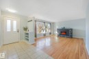 Entryway and living area featuring ceramic tile flooring, hardwood flooring, a stone fireplace, and large windows - 15704 91 Avenue, Edmonton, AB  - Indoor With Fireplace 