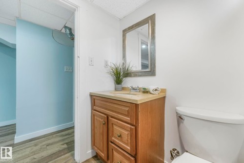 Bathroom featuring a wooden vanity with a light-colored countertop and a mirror with a decorative frame - 15704 91 Avenue, Edmonton, AB - Indoor Photo Showing Bathroom