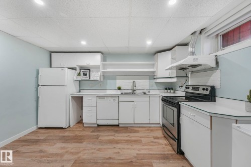 Kitchen featuring white cabinetry, wood-look flooring, a stainless steel electric stove, and a white refrigerator - 15704 91 Avenue, Edmonton, AB - Indoor Photo Showing Kitchen