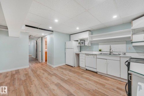 The property features a kitchen area with white cabinetry, a sink, and a dishwasher, complemented by light-colored flooring - 15704 91 Avenue, Edmonton, AB - Indoor Photo Showing Kitchen