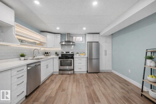 Well-appointed kitchen featuring light wood-style flooring, white cabinetry, and stainless steel appliances - 15704 91 Avenue, Edmonton, AB - Indoor Photo Showing Kitchen With Upgraded Kitchen