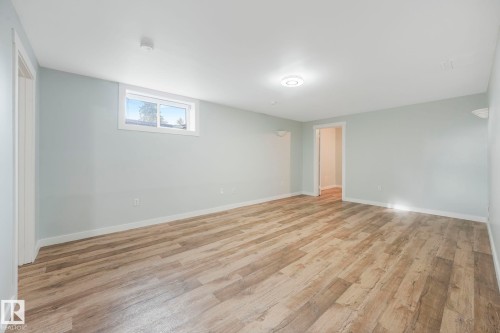 This spacious room features light-toned walls, wood-look flooring, and a window providing natural light - 15704 91 Avenue, Edmonton, AB - Indoor Photo Showing Other Room