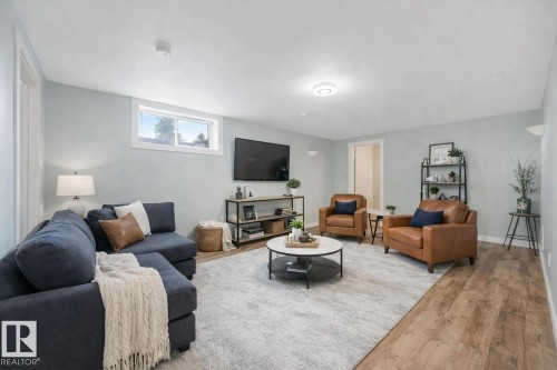 Living area featuring light blue walls, a window providing natural light, and wood flooring - 15704 91 Avenue, Edmonton, AB - Indoor Photo Showing Living Room