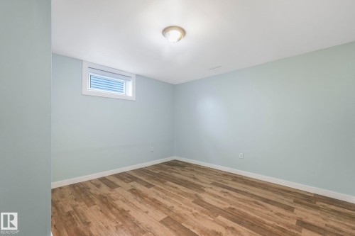This room features light blue walls, wood-style flooring, a window with blinds, and an overhead light fixture - 15704 91 Avenue, Edmonton, AB - Indoor Photo Showing Other Room