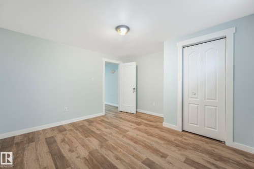 The room features light wood-look flooring, light-colored walls, and a white bi-fold closet door - 15704 91 Avenue, Edmonton, AB - Indoor Photo Showing Other Room