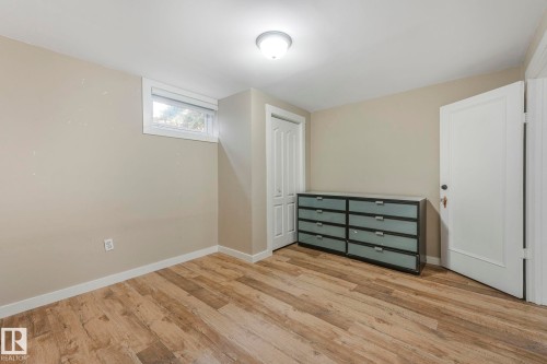 Interior space featuring wood-look flooring, light-colored walls, a window, and a white door - 15704 91 Avenue, Edmonton, AB - Indoor Photo Showing Other Room