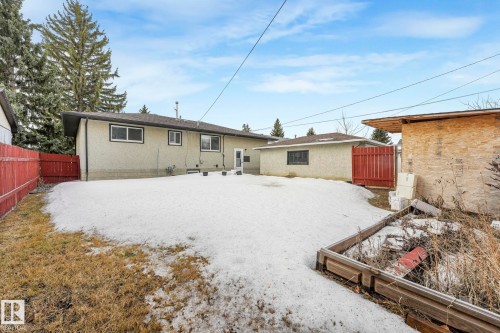 The property features a stucco exterior, a fenced yard, and an external building with a red fence - 15704 91 Avenue, Edmonton, AB - Outdoor With Exterior
