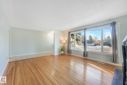 The property features hardwood floors, light-colored walls, and large windows that provide natural light - 15704 91 Avenue, Edmonton, AB - Indoor Photo Showing Other Room