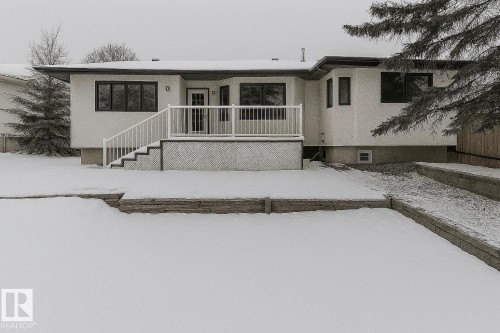 The property features a white exterior with dark-framed windows, a white deck with railings, and steps leading to the yard - 9971 178 Avenue, Edmonton, AB - Outdoor