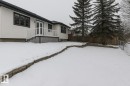 The property features a white exterior with dark trim windows, a white deck with railings and steps, and a spacious yard with mature evergreen trees - 9971 178 Avenue, Edmonton, AB  - Outdoor 
