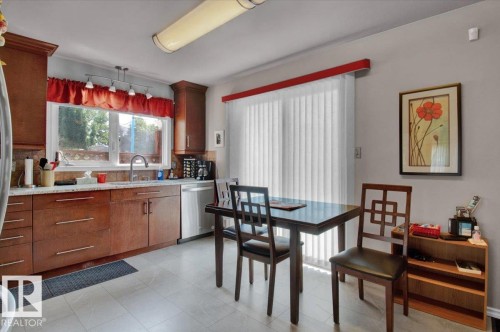 The property features a kitchen with wood cabinetry, a window above the sink, and a dining area with direct access to a sliding glass door - 3523 18A Avenue, Edmonton, AB - Indoor Photo Showing Dining Room