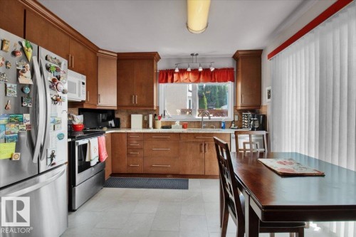 The kitchen features wooden cabinetry, stainless steel appliances, a window above the sink, and light-colored flooring - 3523 18A Avenue, Edmonton, AB - Indoor Photo Showing Kitchen
