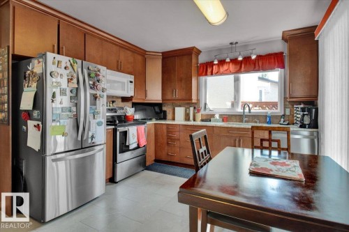 The kitchen features wood cabinetry, stainless steel appliances, and a window above the sink - 3523 18A Avenue, Edmonton, AB - Indoor Photo Showing Kitchen