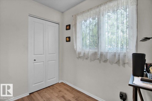 This room features hardwood flooring, white walls, and a window with lace curtains providing natural light - 3523 18A Avenue, Edmonton, AB - Indoor Photo Showing Other Room