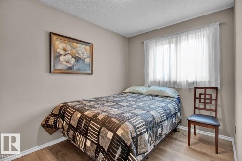 Bedroom featuring neutral-toned walls, hardwood floors, and a window with sheer white curtains - 3523 18A Avenue, Edmonton, AB - Indoor Photo Showing Bedroom