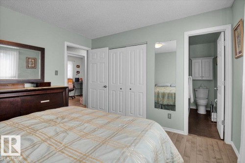 This bedroom features light green walls, light hardwood flooring, and white closet doors - 3523 18A Avenue, Edmonton, AB - Indoor Photo Showing Bedroom